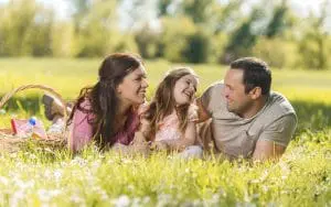 Happy mid adult parents talking to their little daughter while being on picnic during spring day.