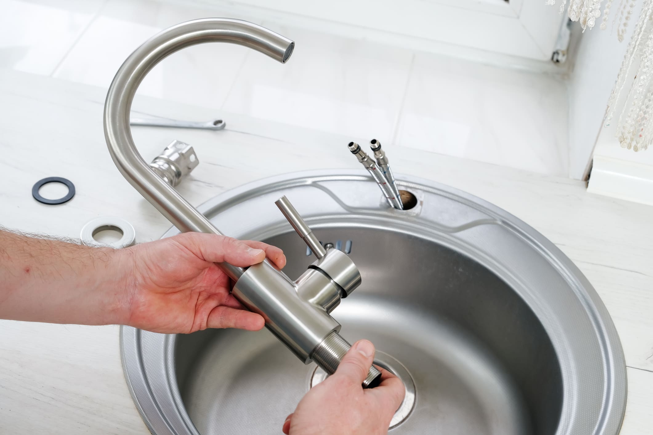 Close-up plumber hands holds a new faucet for installing into the kitchen sink, plumbing work or renovation