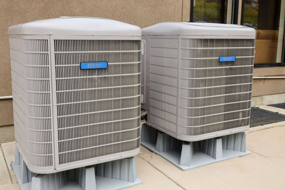 AC replacement in Orem UT shown with two newly installed outdoor condenser units placed on a concrete pad beside a residential home. Western Heating, Air & Plumbing provides AC replacement services in Orem, Utah, helping homeowners upgrade aging cooling systems with modern equipment. The image shows clean installation work, proper spacing, and elevated unit placement for airflow and performance. Homeowners in Utah County rely on Western Heating, Air & Plumbing for reliable air conditioning replacement and efficient cooling solutions. Call Western Heating, Air & Plumbing in Orem UT for AC replacement services and system upgrades.
